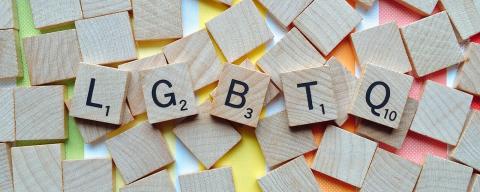 Scrabble letters with rainbow colors underneath spell out LGBTQ.