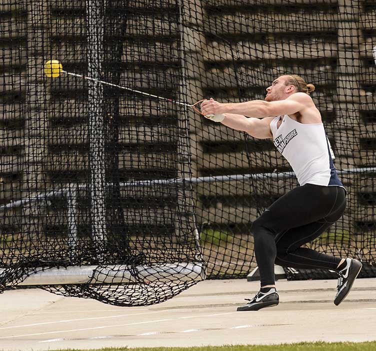 UNH men's track and field student swinging a ball on a rope