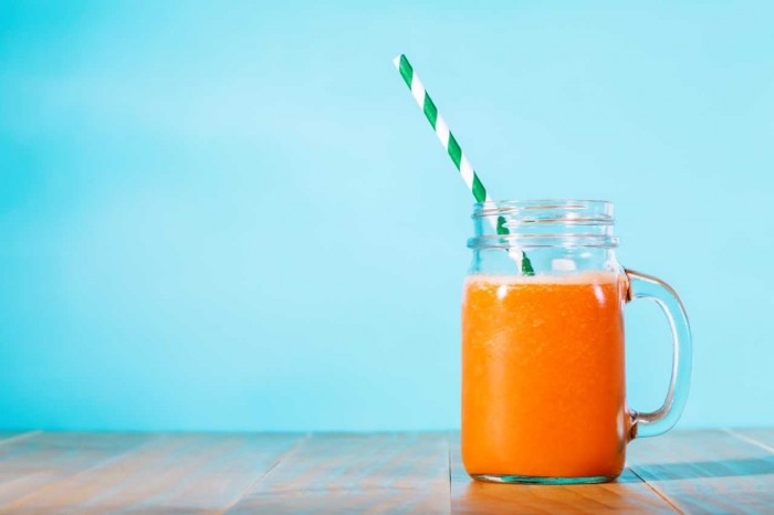 orange smoothie in front of a blue background