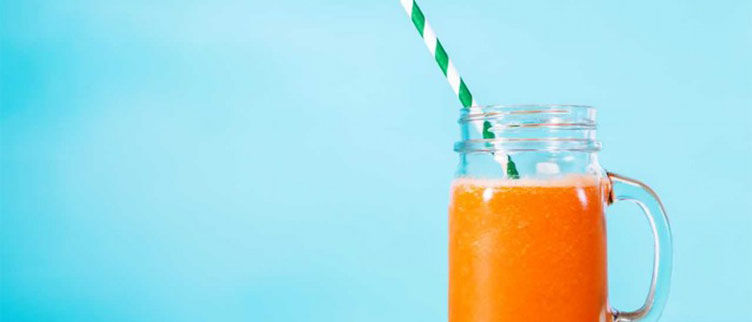 orange smoothie in front of a blue background