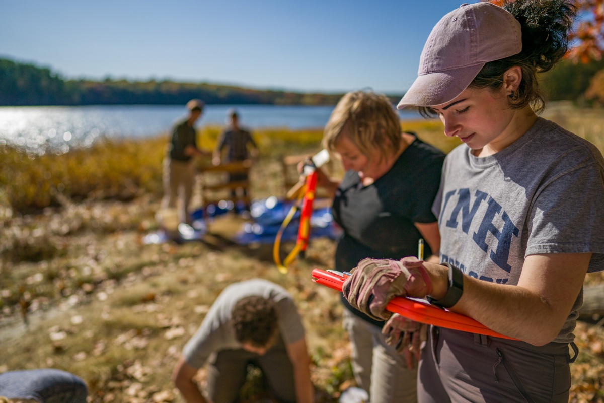 Student takes field notes near Great Bay for archaeological survey project. 