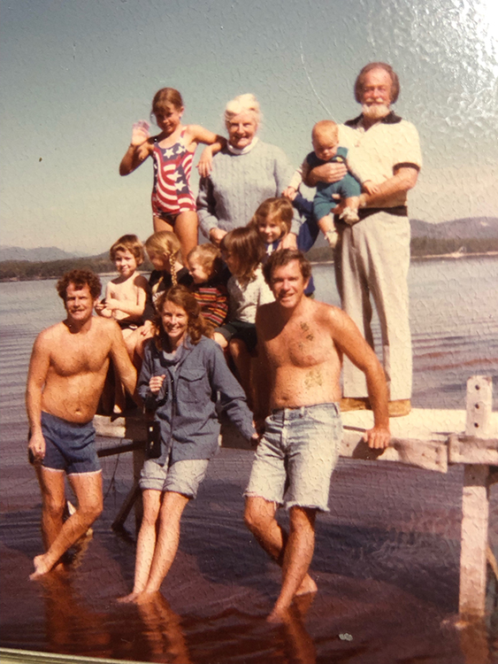 A family portrait on the beach featuring five adults and seven chilidren