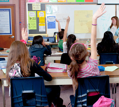 children in the classroom with their hands up