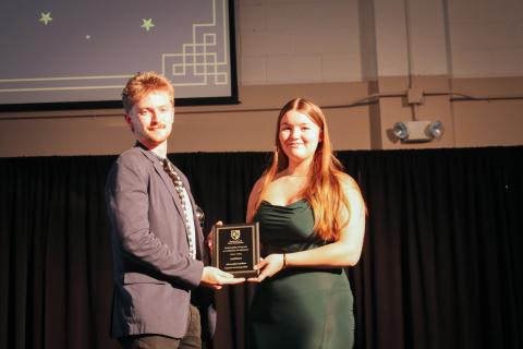 Two people holding an award and smiling to the camera