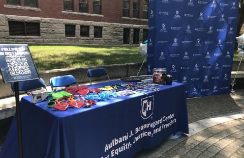 Photo booth set up outside with funky glasses and chalkboard signs, table with blue tablecloth and blue photo background