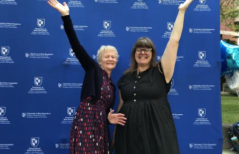 Two library staff members with their arms up in the air in front of blue photo background