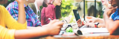 Students collaborate at table with computers