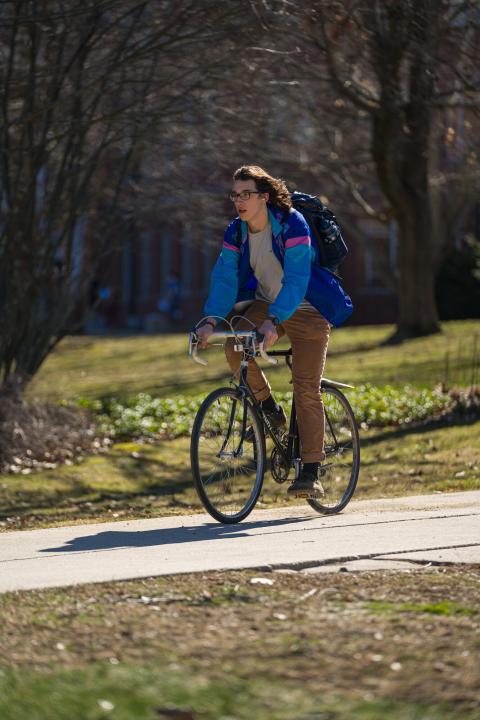 Student rides on bicycle through campus