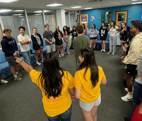 Students standing in a circle attending a social event. 