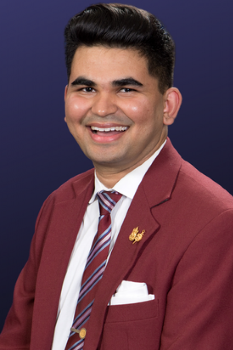 Headshot of Yashwant Prakash Vyas smiling while wearing a maroon jacket and striped tie. 