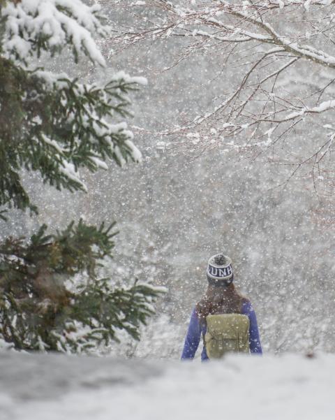 UNH student walking on snowy pathway