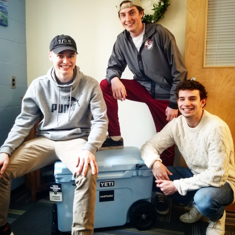 Photo of three students sitting on a Yeti cooler prize