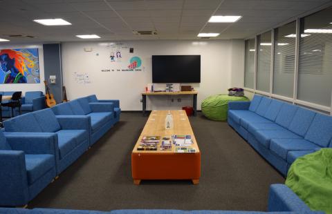 Long blue couches forming a u-shape facing a TV on the wall with a low table in the center