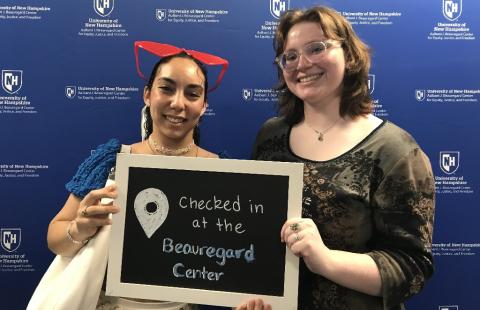Two first year visitors at the Beauregard Center holding a sign that says "Checked in at the Beauregard Center) in front of a blue background