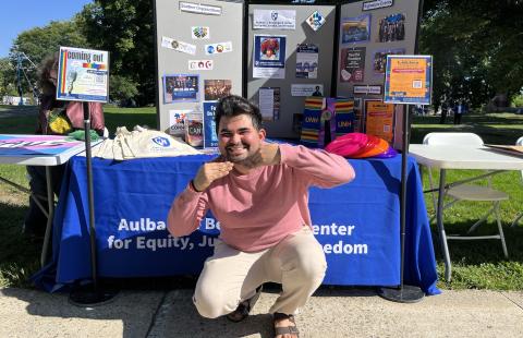Director Yashwant crouching in front of Beauregard Center table at U-Day
