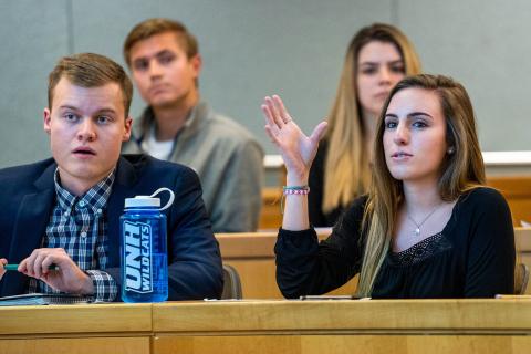 Students in lecture. One is raising their hand.