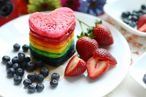 stack of rainbow colored pancakes blueberries, strawberries