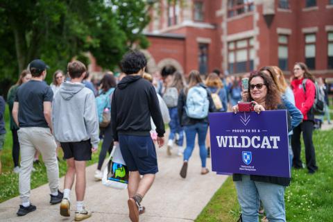 Large group of students walk through UNH campus