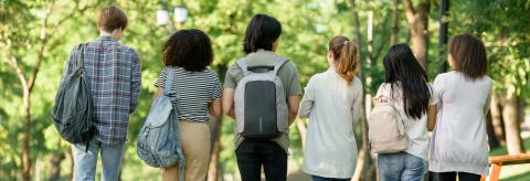Six students with backpacks walk away from the camera