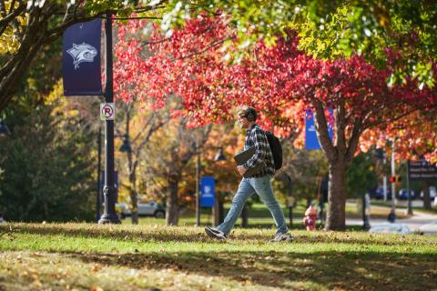 Student walking across the UNH campus in fall.