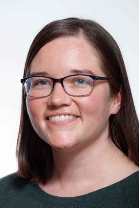 woman with brown shoulder-length hair and dark glasses smiles at camera
