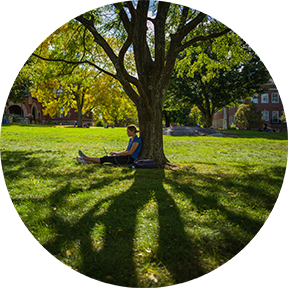 UNH Student seated on lawn on UNH Campus