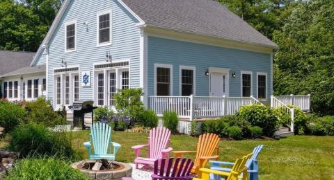 The backyard of a blue house with lawn chairs