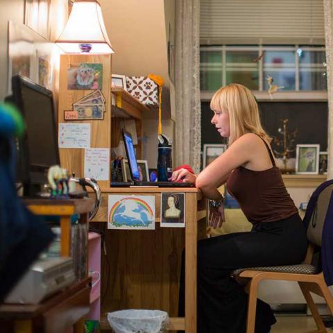 A student at the desk in their dorm room