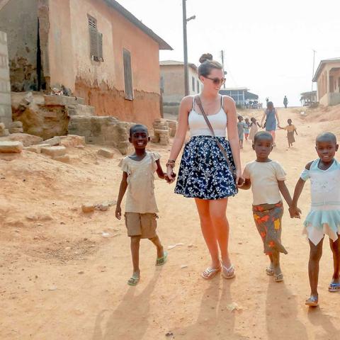 A woman walks with children through their town