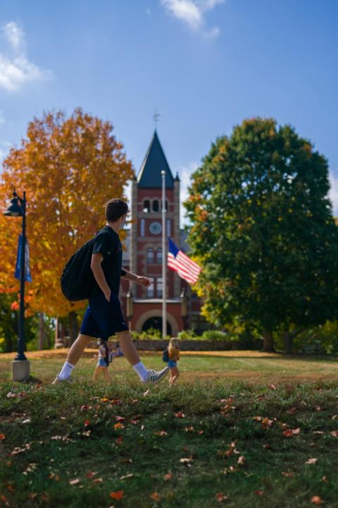 A male student walking in front of Thompson Hall