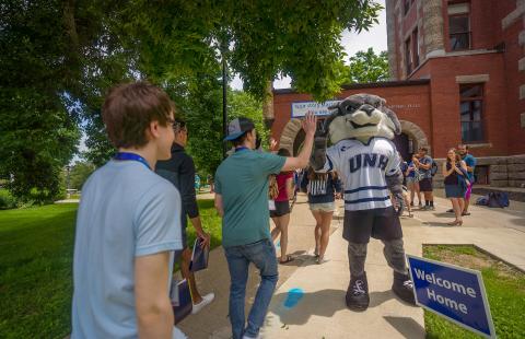 Wildcat mascot high fiving new students walking under the T Hall Arch 