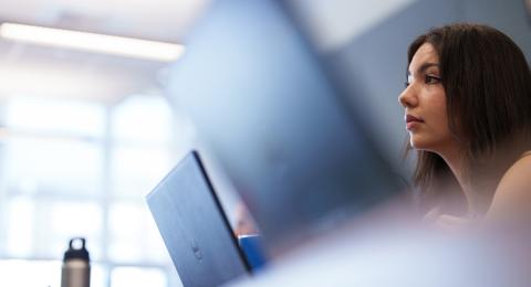 UNH student sitting in front of laptop in class