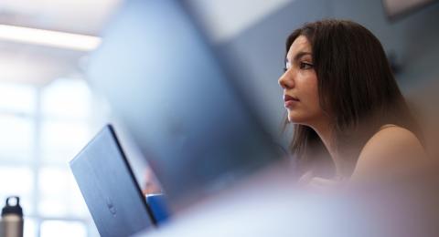 UNH student sitting in front of laptop in class
