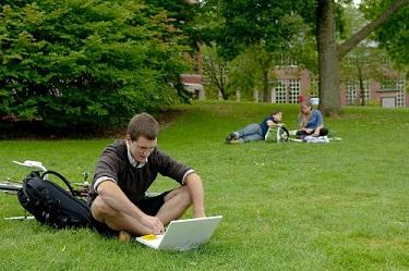 student working on laptop on t-hall lawn