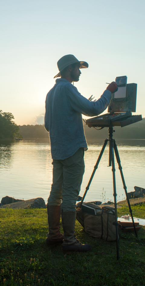 Man standing outside with easel