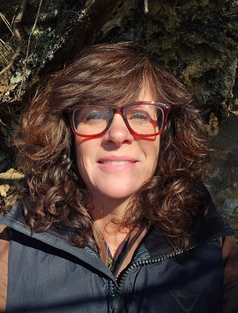woman with glasses smiling into the camera