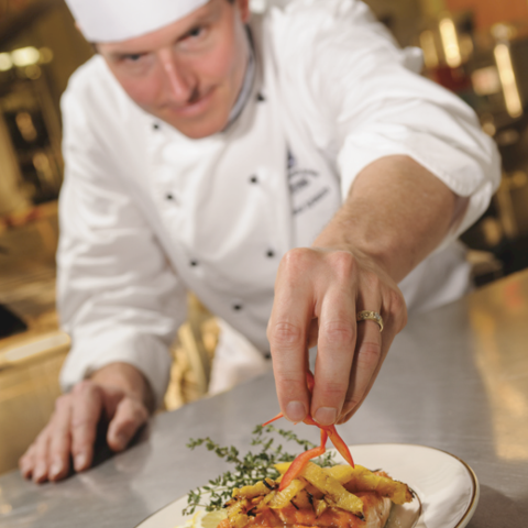 Catering Chef Jack adding finishing touches to a plate of food.
