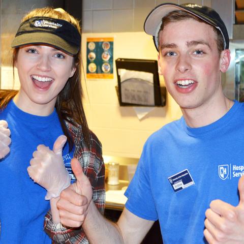 Students working in a dining hall with thumbs up