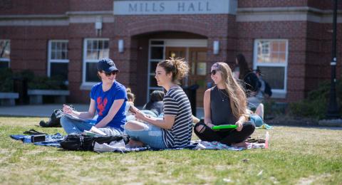 students sitting on lawn outside of Mills Hall