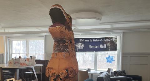 Student in Dinosaur Costume Serving Donuts