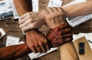 A photo of four different hands grabbing the wrist of the person to the right