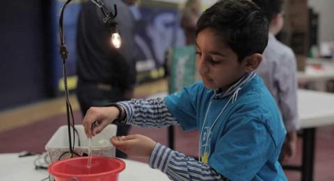 Young inventor stirring in a sand pail