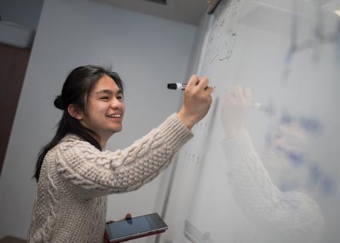 mathematics student writing an equation on a whiteboard