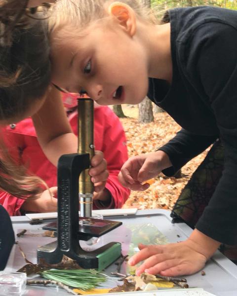 a young student uses a microscope to get a closer look at a soil sample