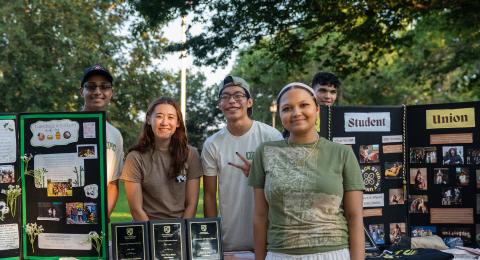 Students standing next to displays about their student organization at University Day. 