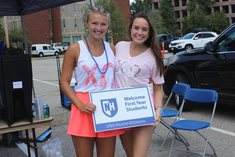 Two sorority women posing with a UNH sign
