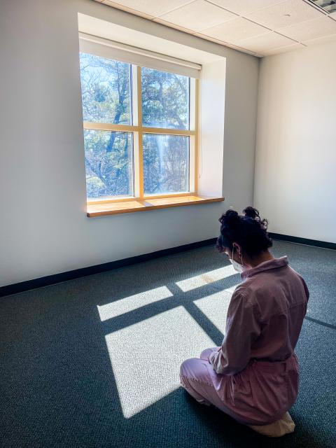 Student meditating in front of window