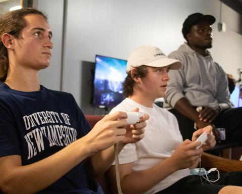 Three students sitting on couch playing video games
