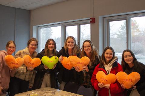 Students holding up stuffed heart pillows