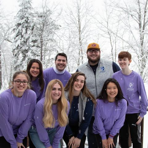 Group of students posing outside with snow falling.